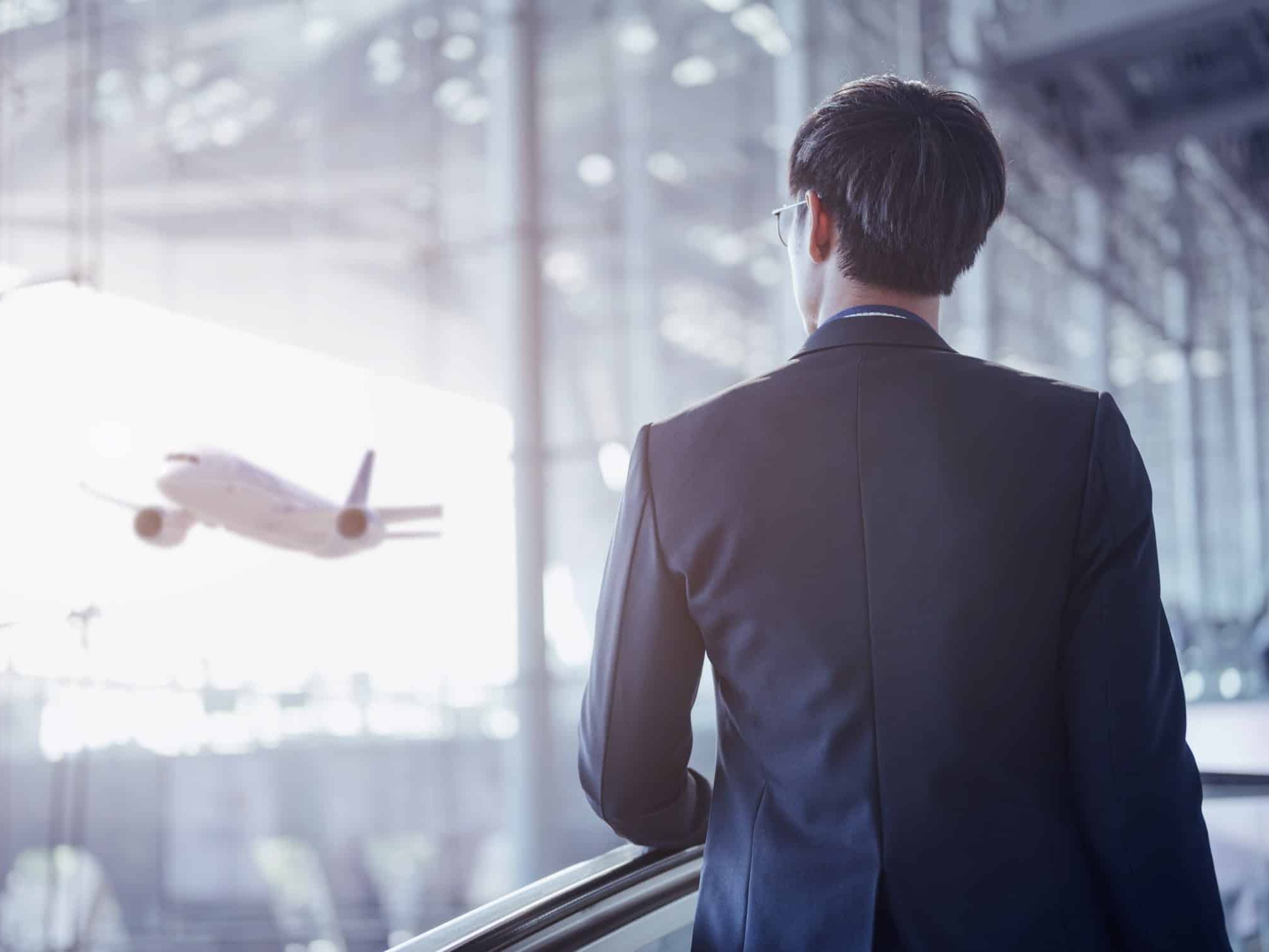 Businessman moving to terminal gate by escalator for check in boarding with luggage at the airport. HTT Corporate Security